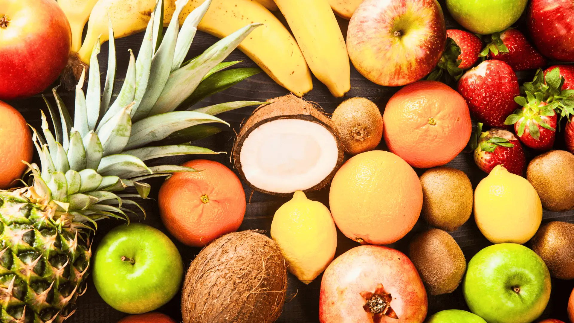 Vista superior de frutas como piña, plátanos, manzanas, naranjas y coco